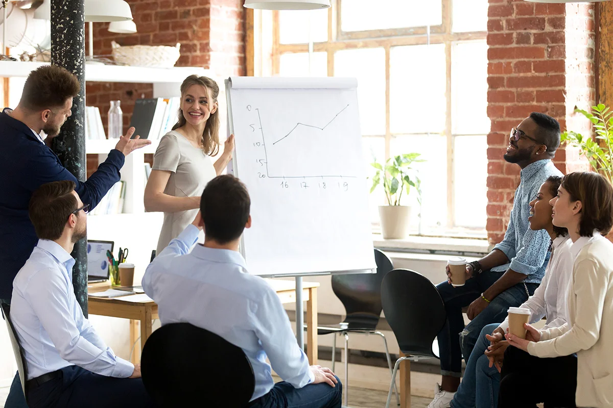 A small business having a meeting in a brightly lit office, with a chart in the center, showing the concept of growing businesses and changing IT needs