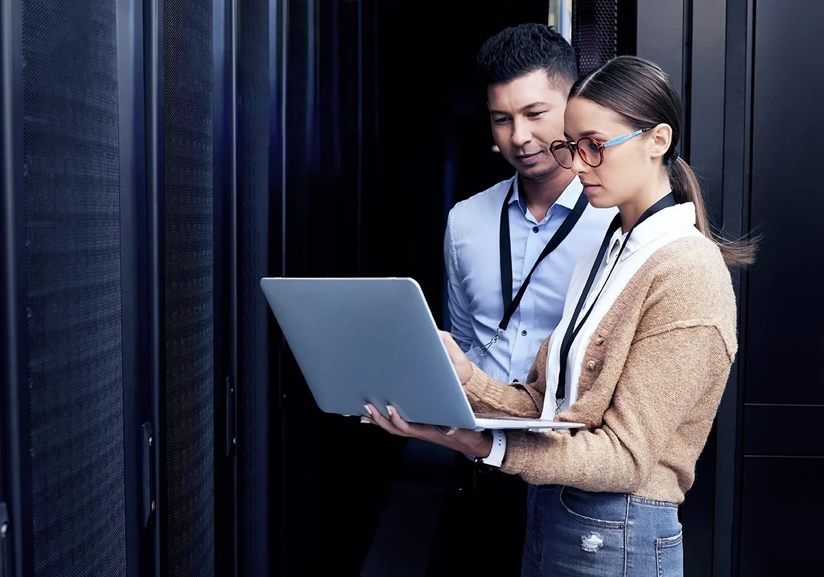 Two IT professionals standing with a laptop, showing the concept of a managed service provider (MSP)